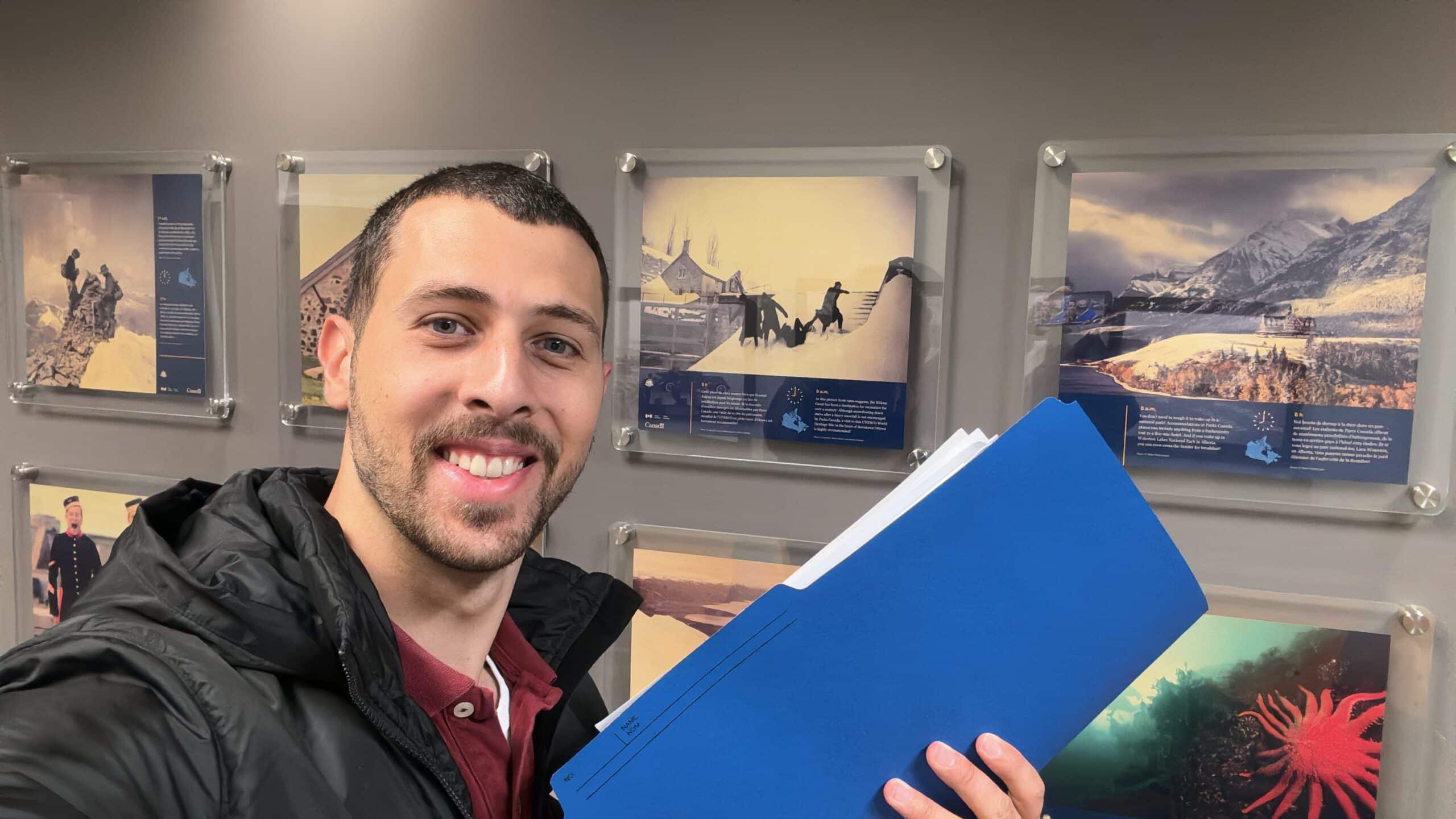 Yaseen Hemzawi holds up his Canadian work permit with a proud smile after waiting eight months to receive it.