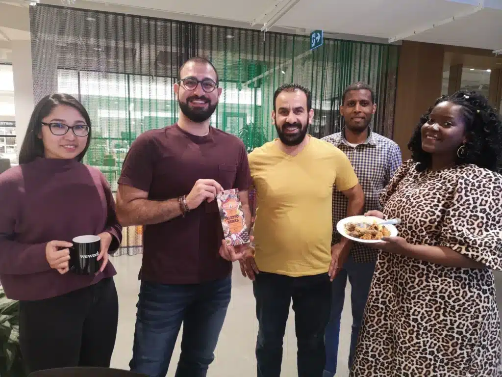 Rahima, a newcomer to Canada, stands smiling beside Dawit, a Jumpstart Refugee Talent manager, during a community event. Both are warmly dressed and appear engaged in a welcoming, multicultural gathering.