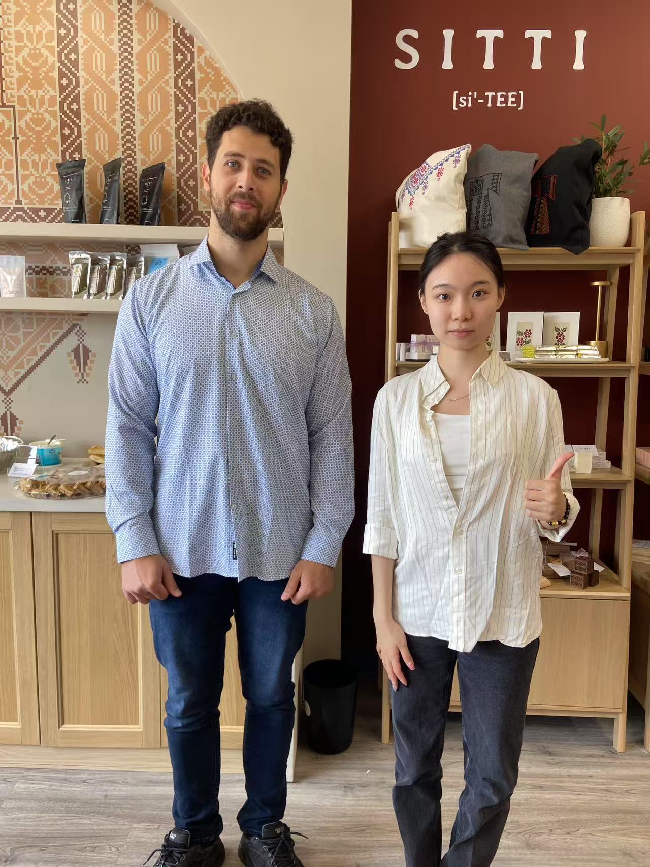 Yaseen Hemzawi and Ya Zeng smiling together at the SITTI storefront during the 2025 World Refugee Day celebration.