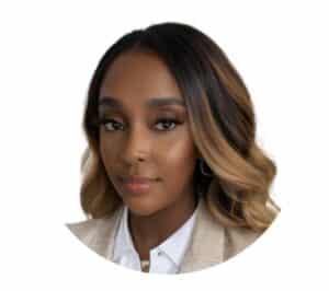 A woman with shoulder-length wavy hair styled in dark brown and caramel tones is facing the camera with a calm expression. She is wearing a beige blazer over a white button-up shirt and gold hoop earrings. The background features a circular design with blue and yellow accents.