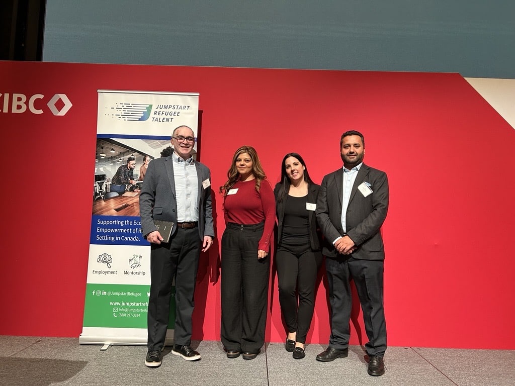 Four Jumpstart Refugee Talent team members — Darrell Pinto, Mina Sharif, Eglys, and Habib — smiling together at the CIBC Speed Networking event in Toronto.