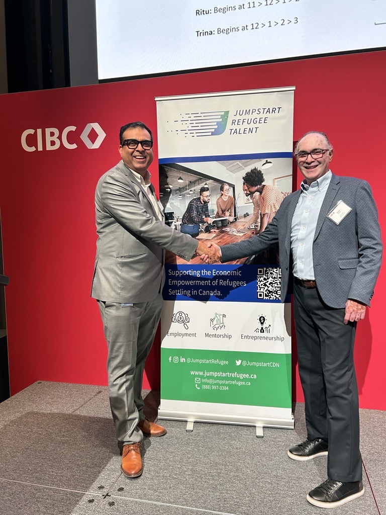 Dhaval Vediya from CIBC and Darrell Pinto from Jumpstart Refugee Talent shake hands at the Speed Networking and Mentorship event, highlighting partnership and collaboration.