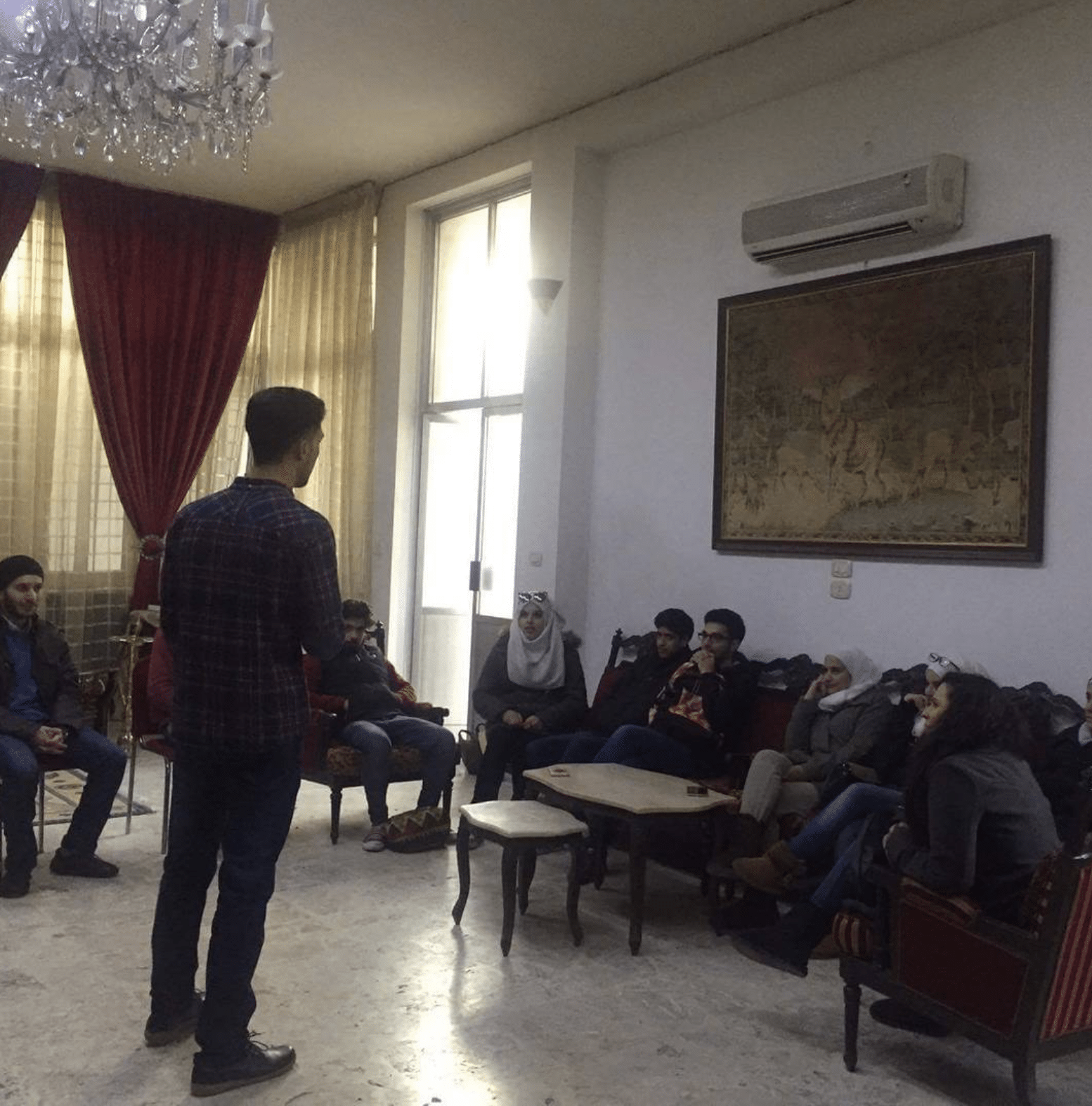 Yaseen standing in front of a group of AFLATEEN team members, giving a workshop on interview preparation and resume writing in 2016.